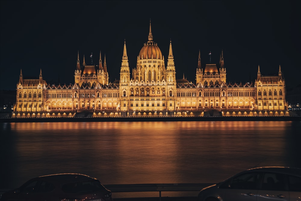 a large building lit up at night with cars parked in front of it