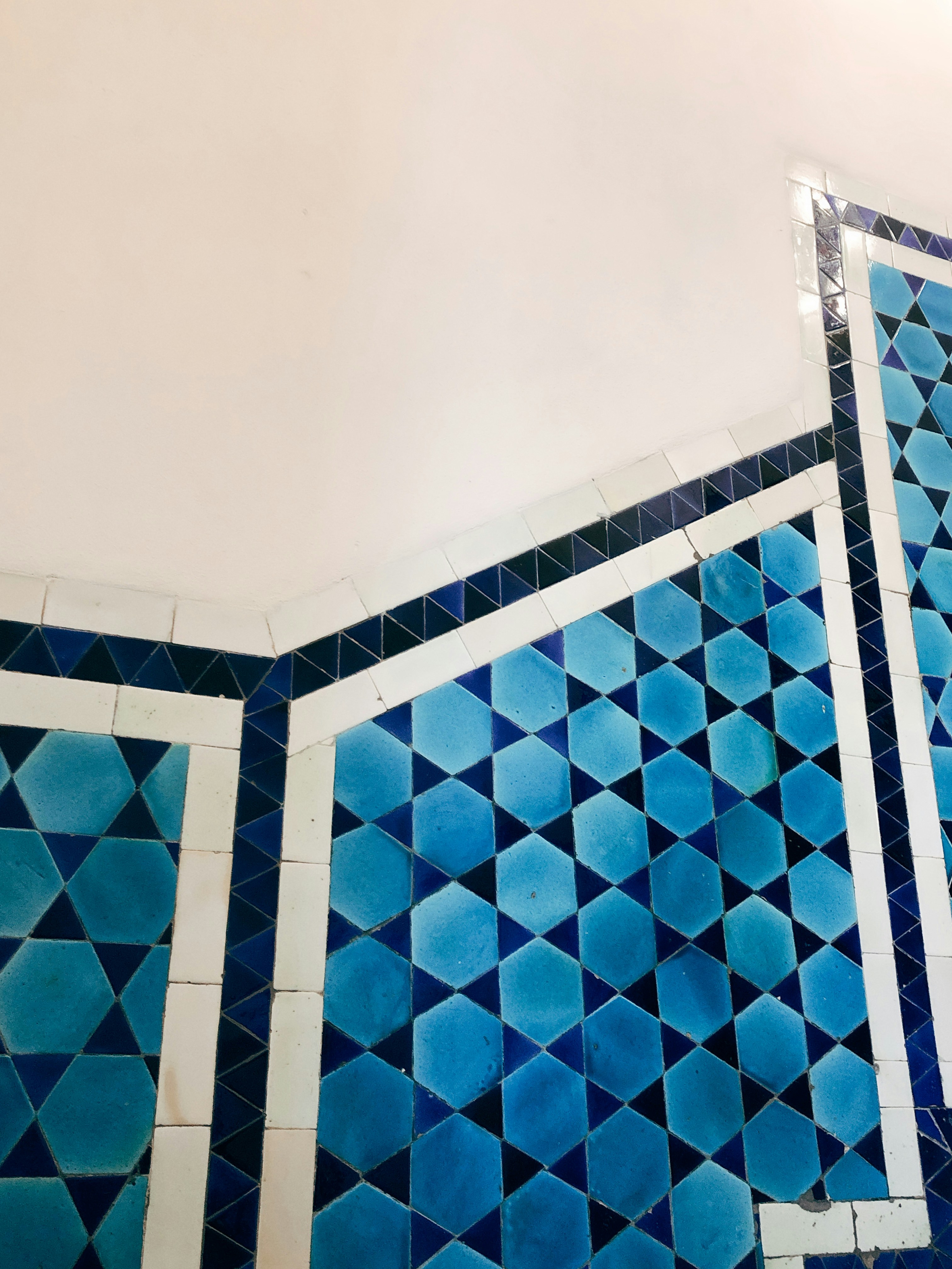 Vibrant blue mosaic ceramic tiles with glossy finish arranged in geometric pattern on bright white wall