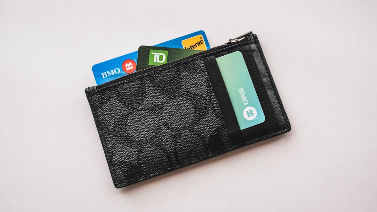 A wallet with credit and debit cards fanned out of it on a desk