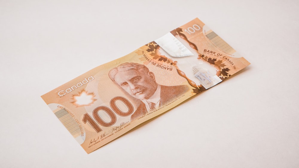 a canadian 100 dollar bill with a knife sticking out of it