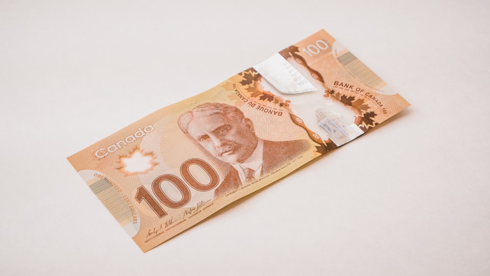 Un billete canadiense de 100 dólares con un cuchillo saliendo de él