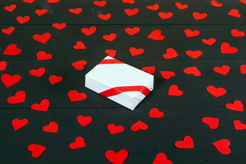 an origami box on a black surface with red hearts