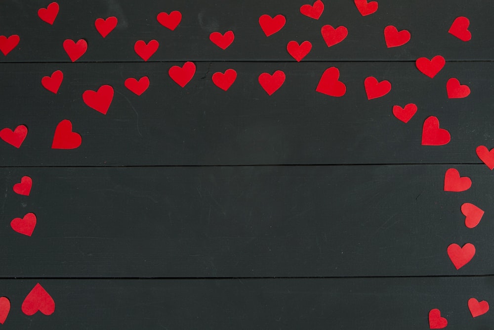Un montón de corazones rojos sobre un fondo negro