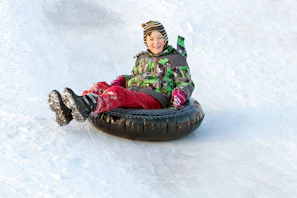 a young boy riding a snow tube down a snow covered slope