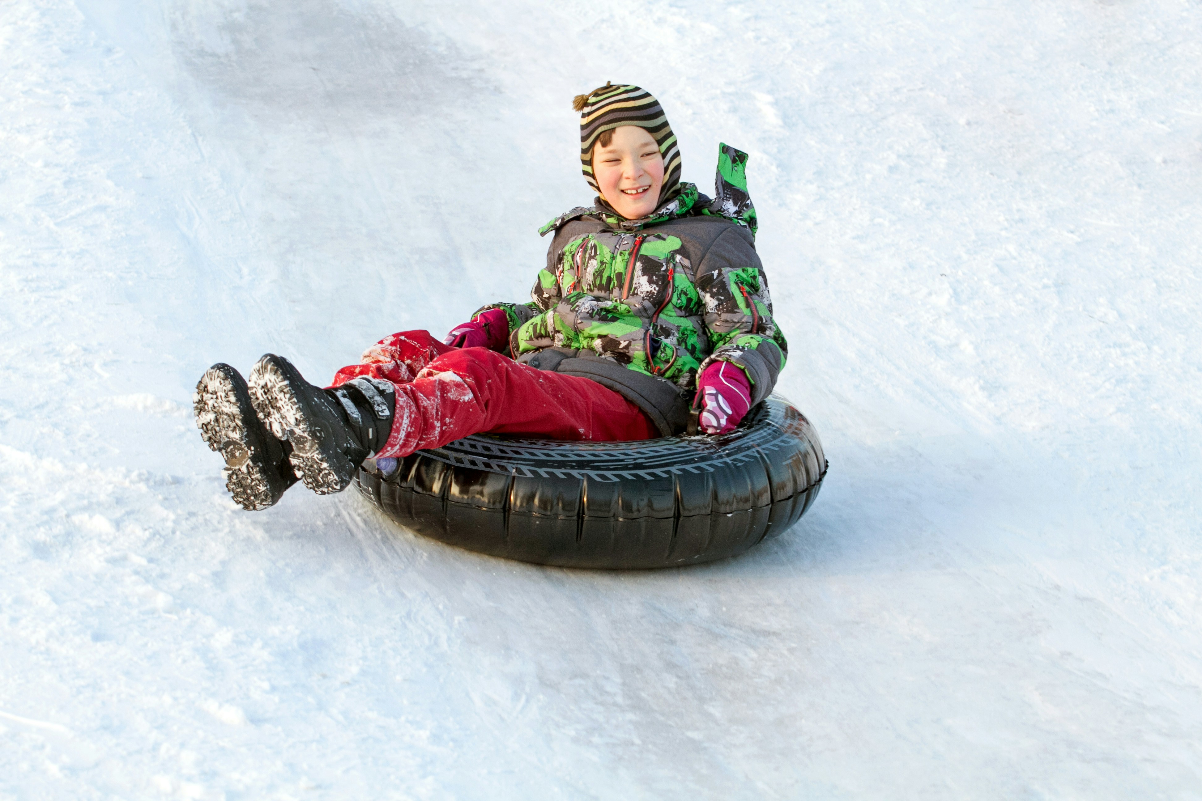 Happy boy with snow tube. Winter fun. Sliding down the hill on a snow tube
