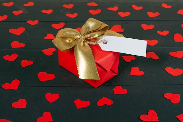 a red gift box with a gold bow and a white card
