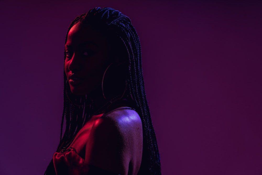 a woman with braids standing in front of a purple background