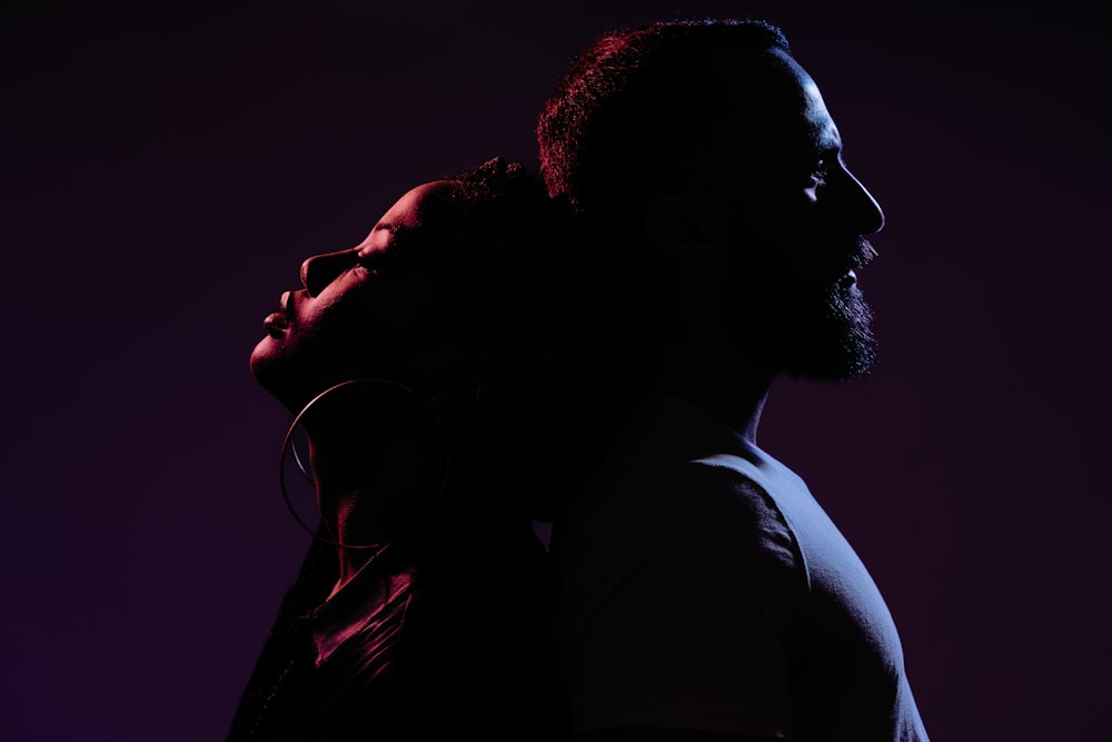 a man and a woman are silhouetted against a purple background