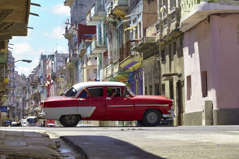 a red and white car driving down a street