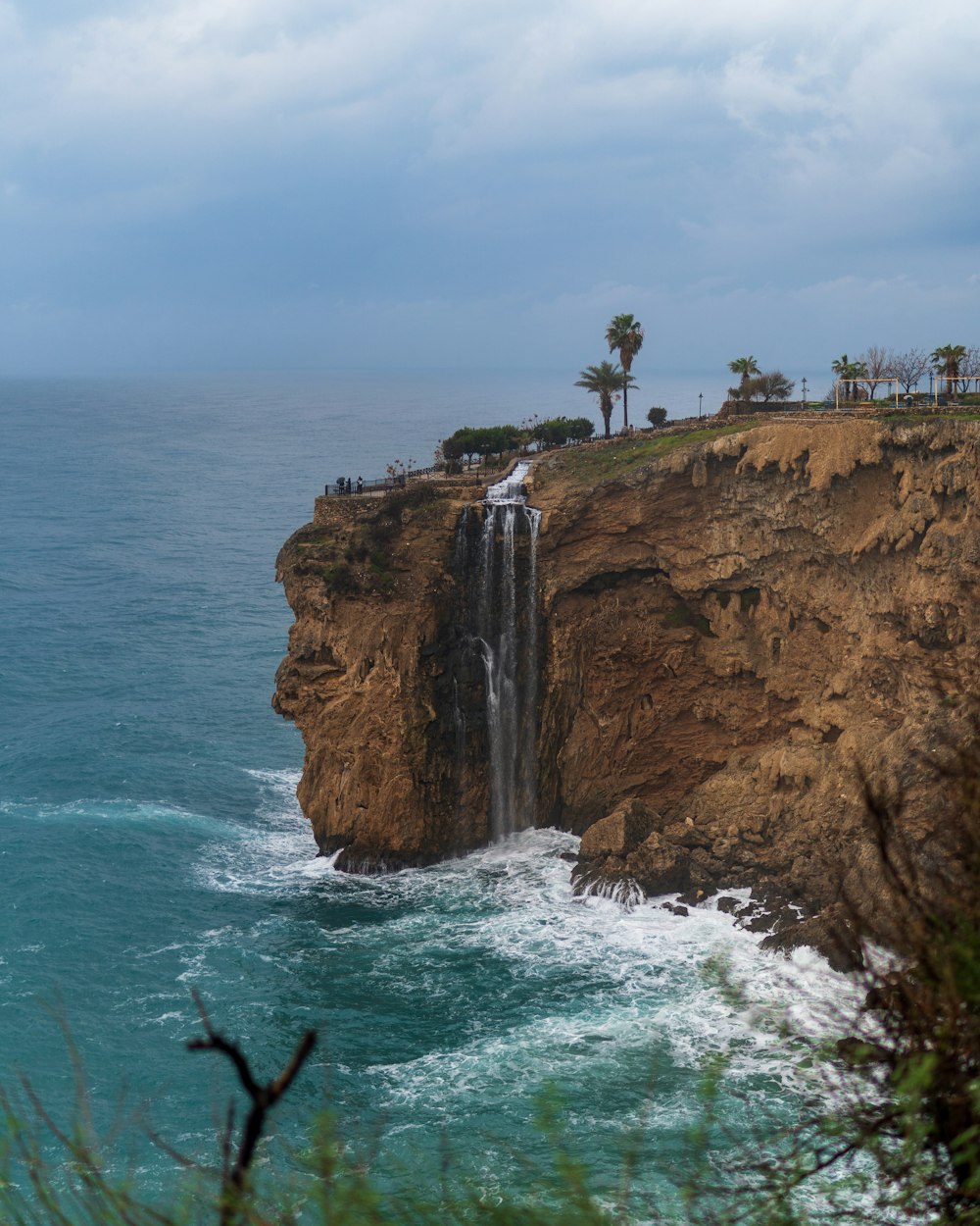 a waterfall on the side of a cliff near the ocean
