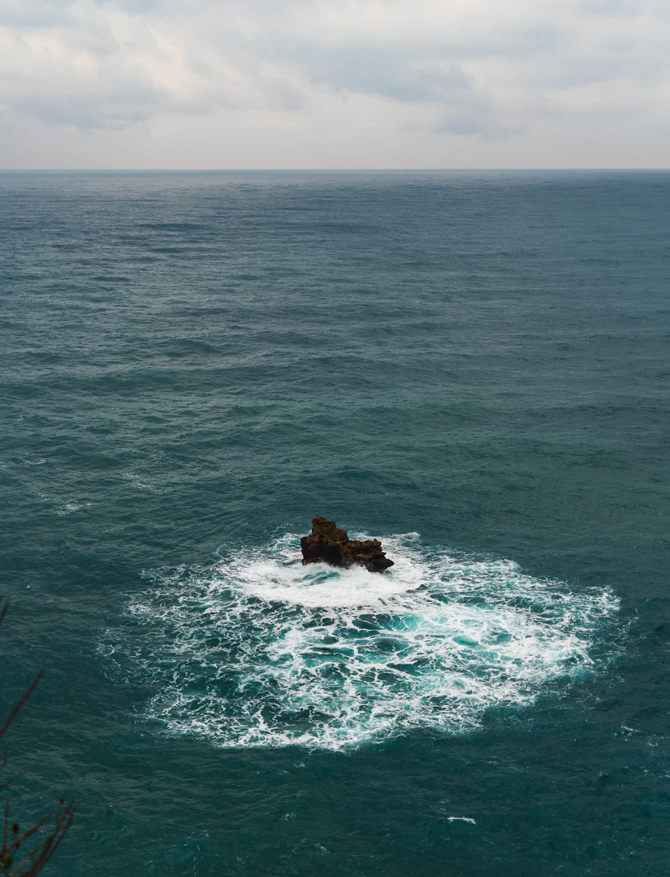 Serene ocean scene with small island in center, surrounded by choppy blue waters