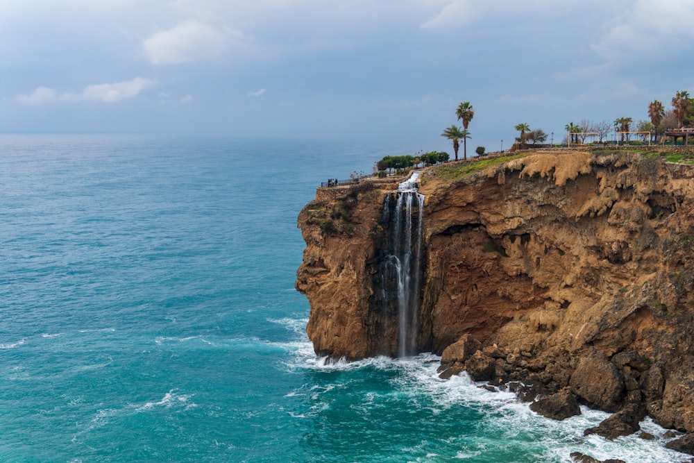 a cliff with a waterfall in the middle of the ocean