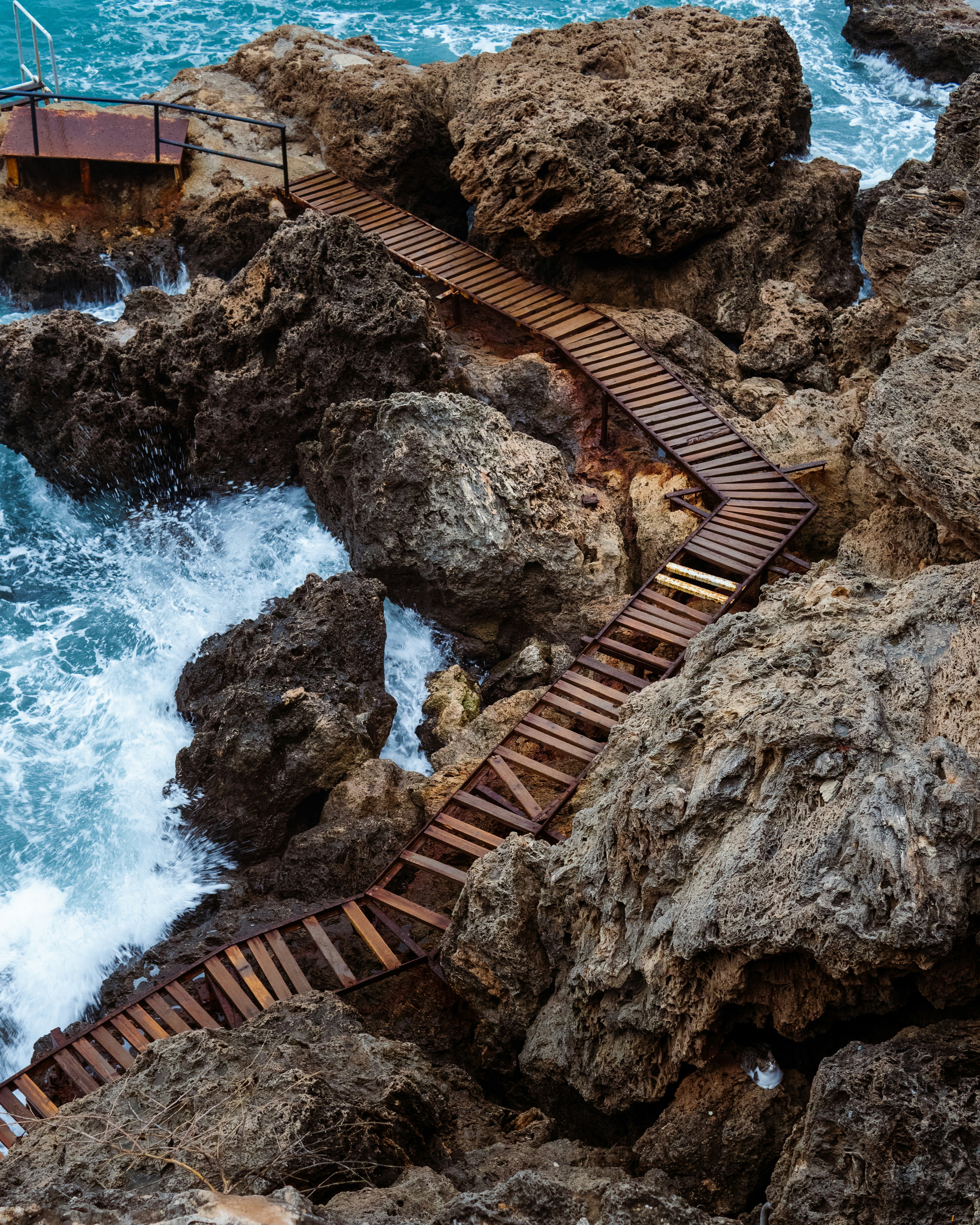 A wooden walkway going over rocks into the ocean photo – Free Fener ...