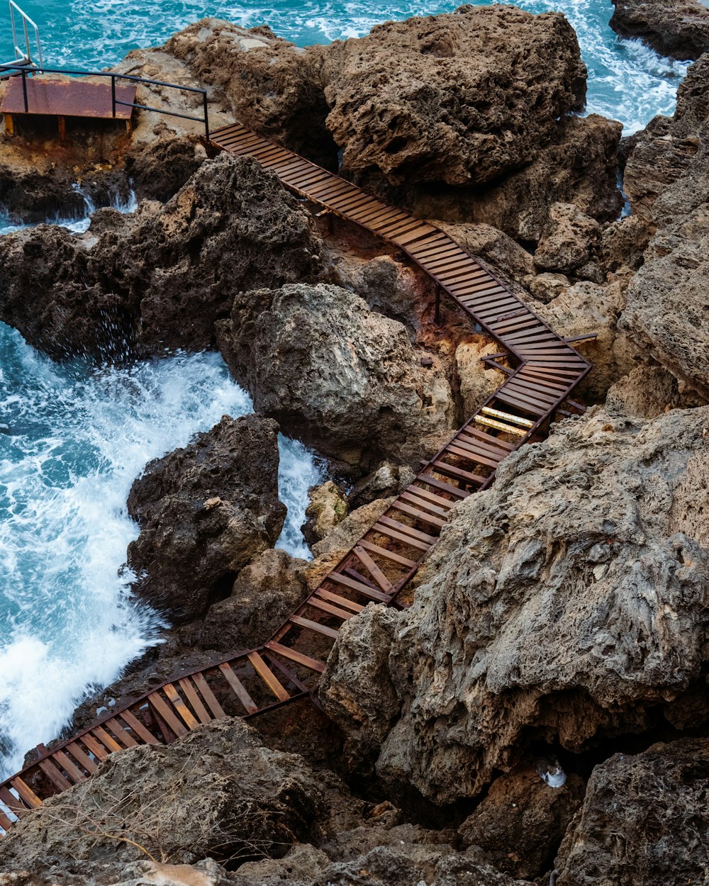 a wooden walkway going over rocks into the ocean