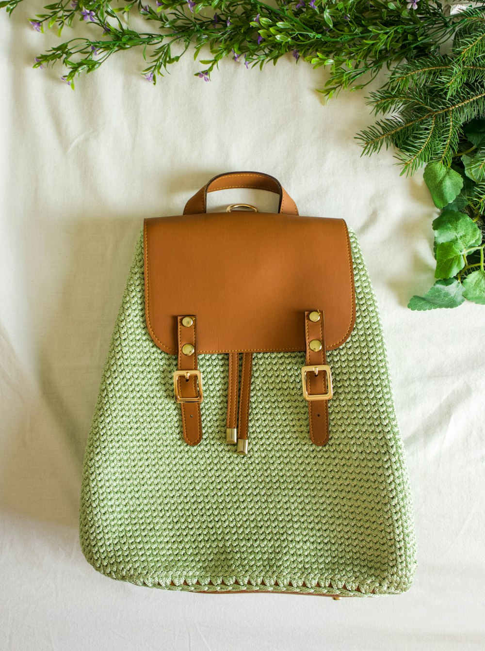 a handbag sitting on top of a bed next to a plant