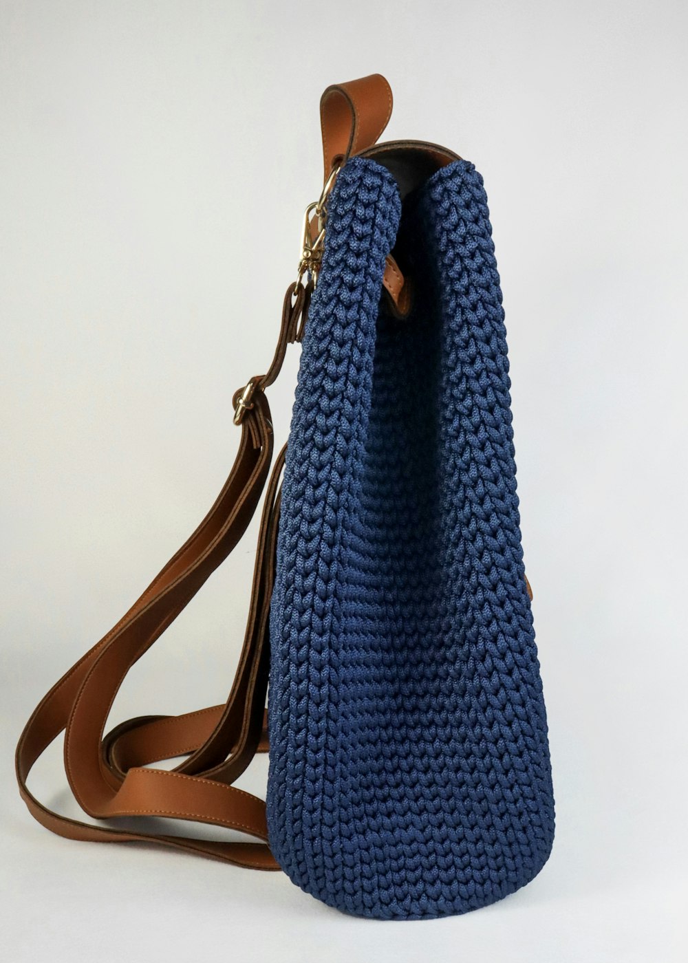 a crocheted blue purse with a brown strap