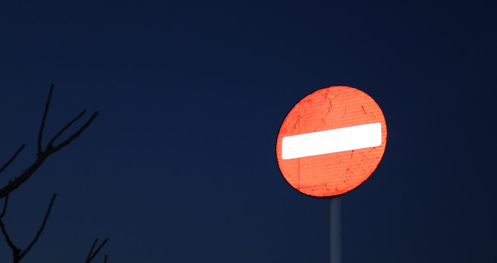 a red and white street sign sitting next to a tree