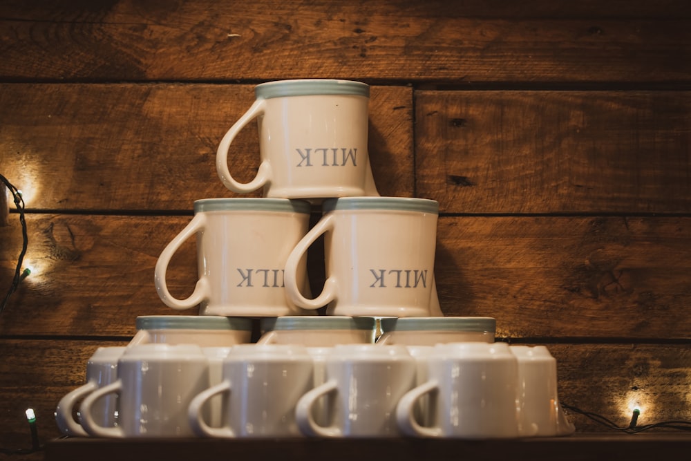 a stack of coffee mugs sitting on top of a wooden shelf