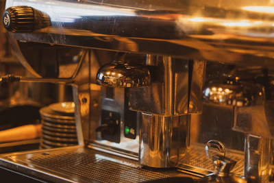 Close-up of a sleek espresso machine with polished metal and warm lighting highlighting its details.