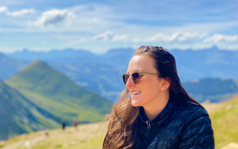 uma mulher com óculos de sol em um topo da montanha