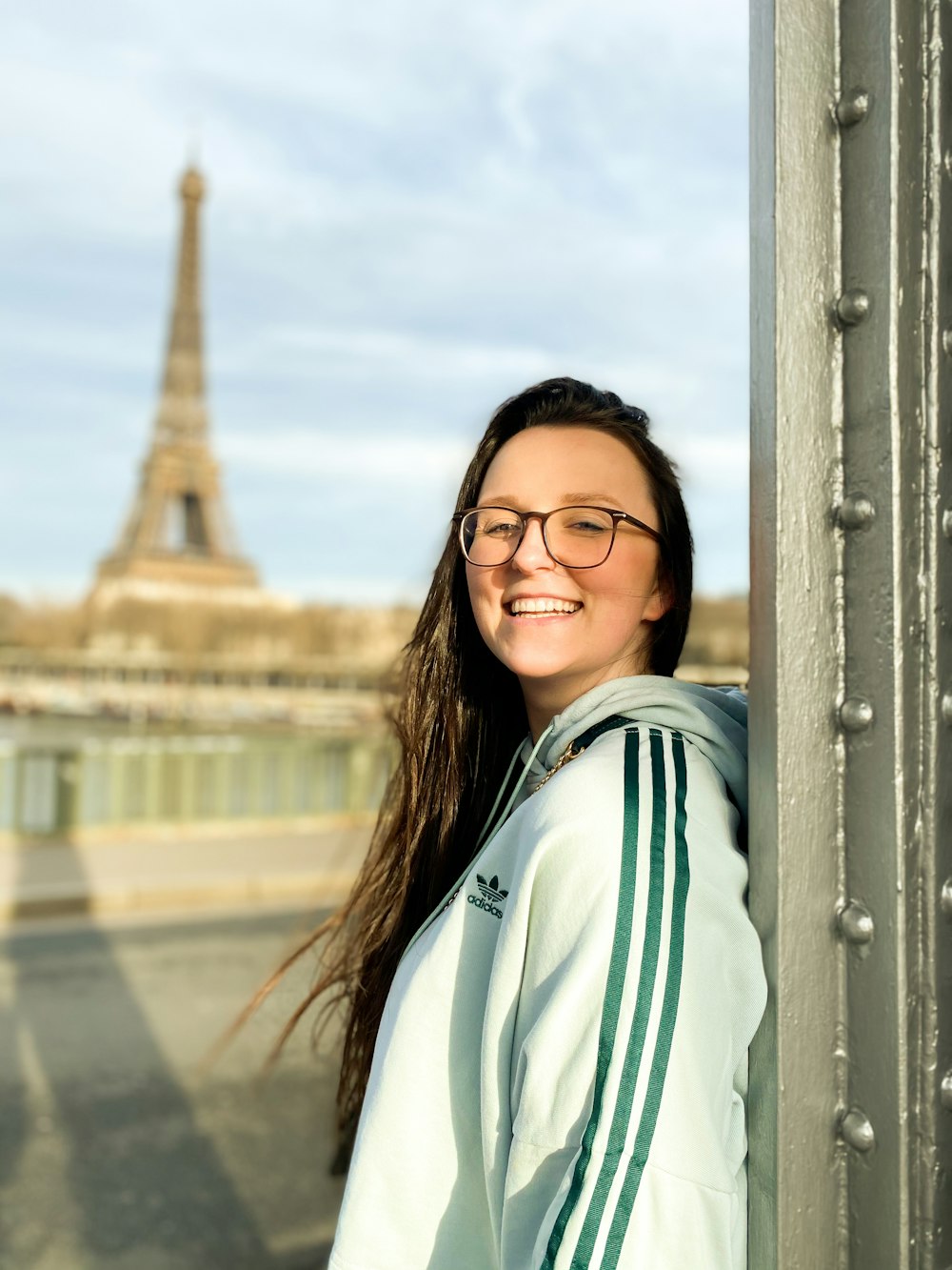 a woman wearing glasses standing next to a pole