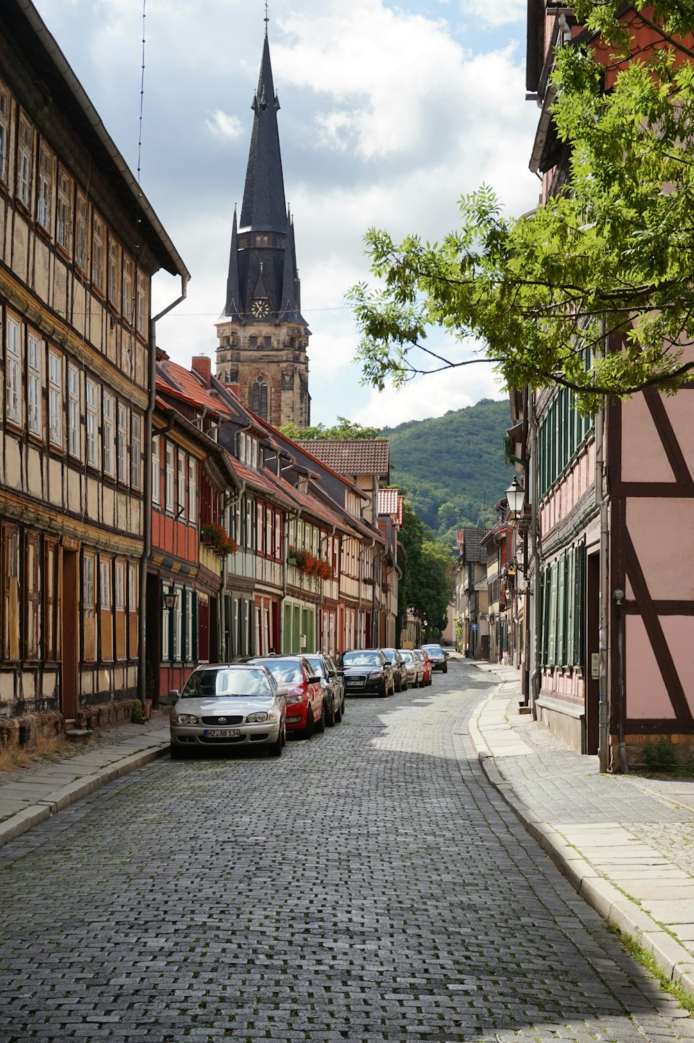 a cobblestone street with a church steeple in the background