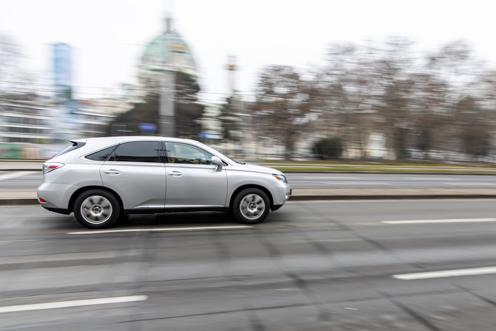 a silver car driving down a city street