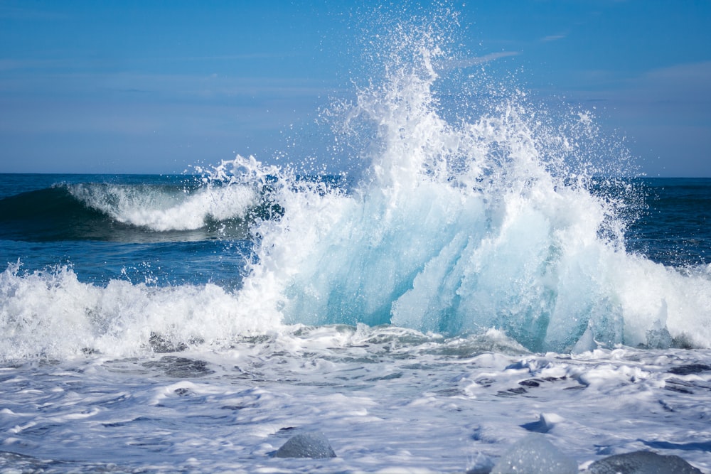 a large wave crashing into the ocean on a sunny day