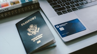 a passport sitting next to a laptop on a desk