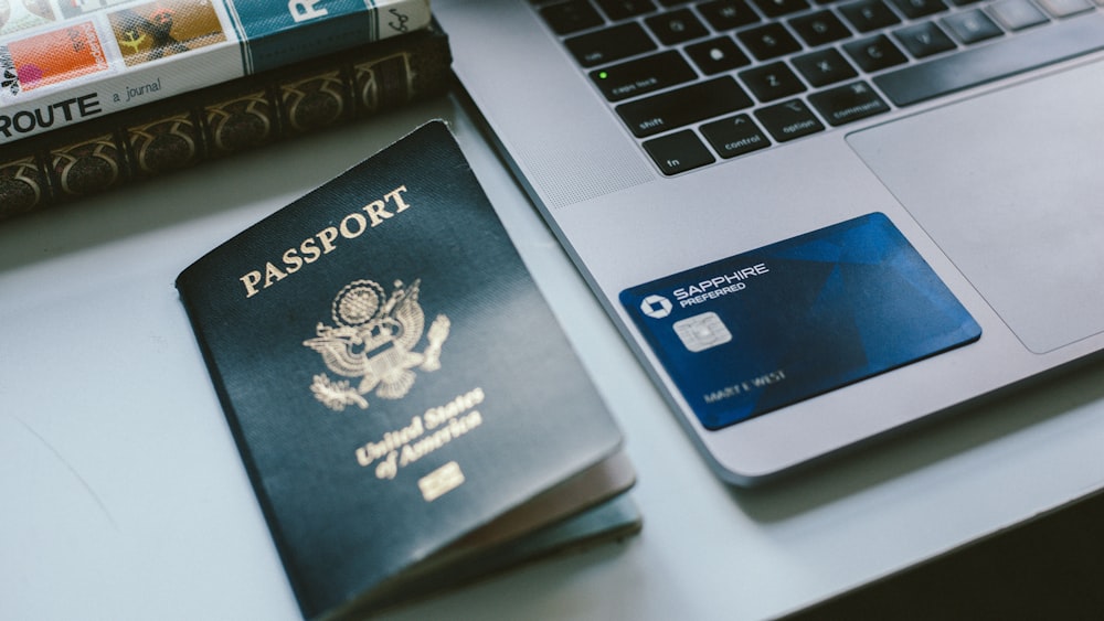 a passport sitting next to a laptop on a desk