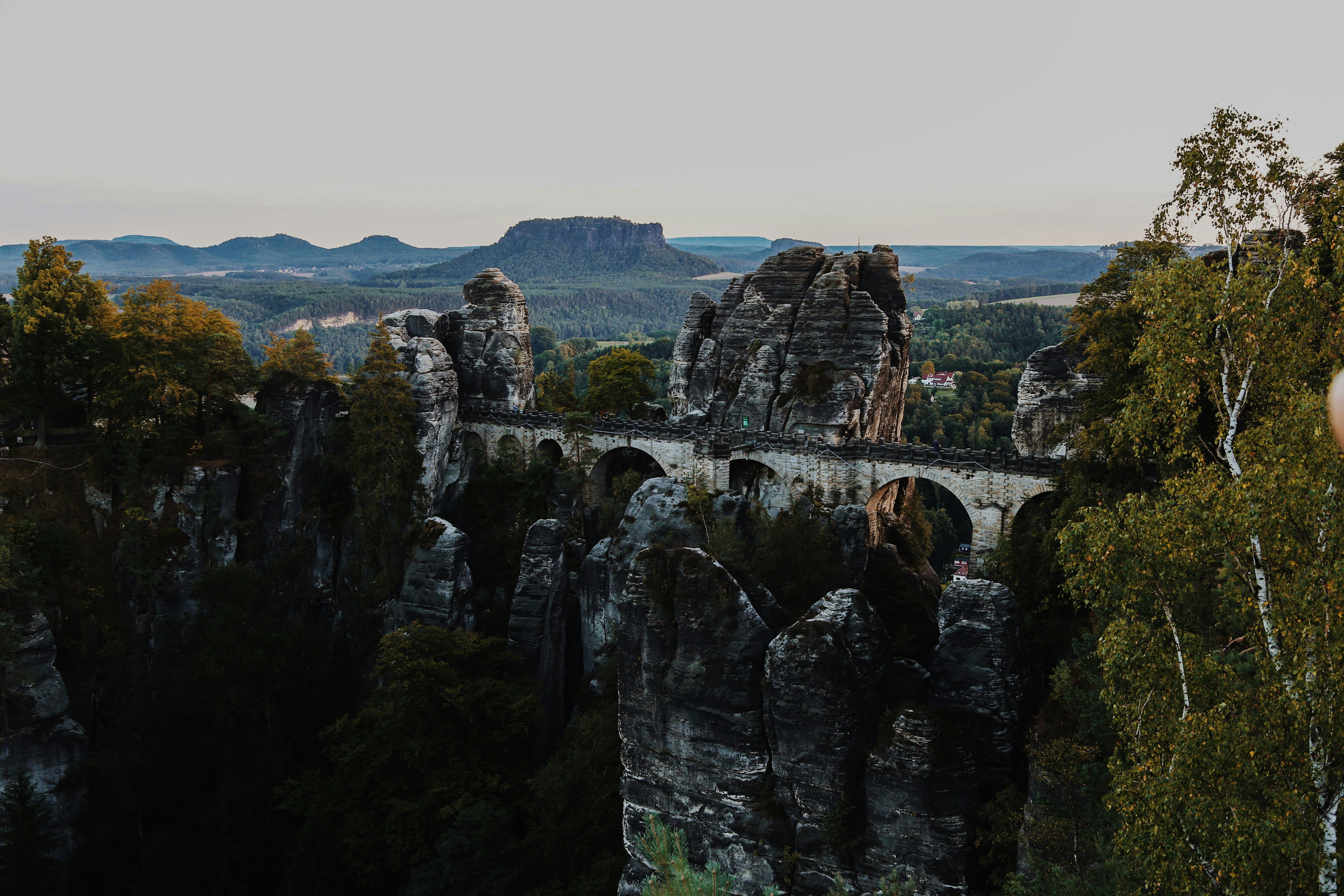 a man standing on top of a mountain next to a bridge