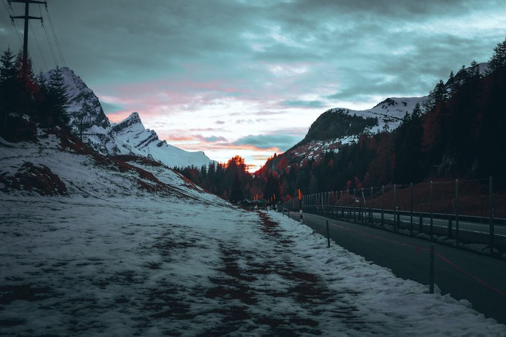 a snow covered road with mountains in the background