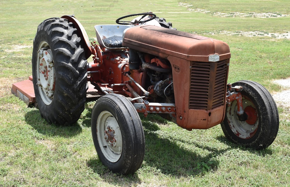 an old red tractor parked in a field