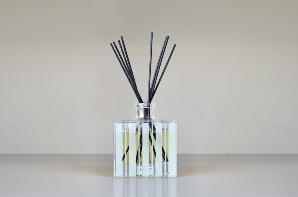 a glass vase with reeds in it on a table