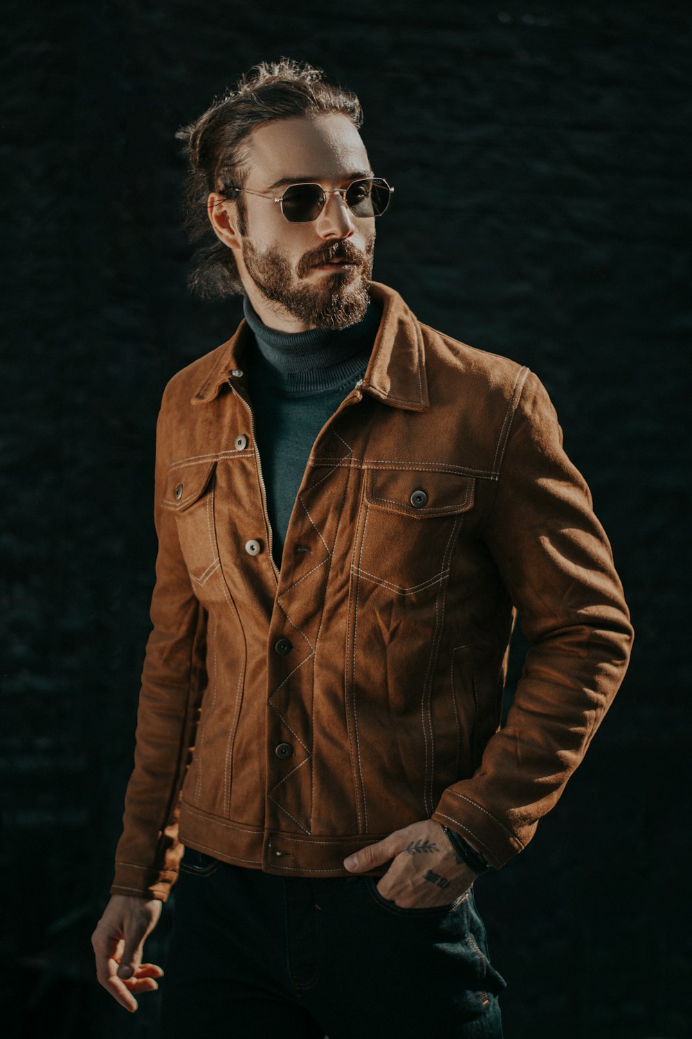 a man wearing a brown jacket and glasses