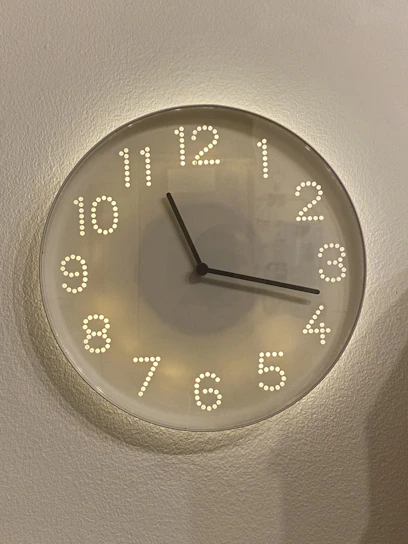 A sleek modern wall clock with bold minimalist numbers hanging on a cozy living room wall.