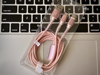 a couple of pink cables sitting on top of a laptop