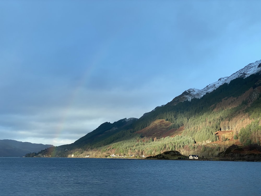 a lake with mountains in the background and a rainbow in the sky