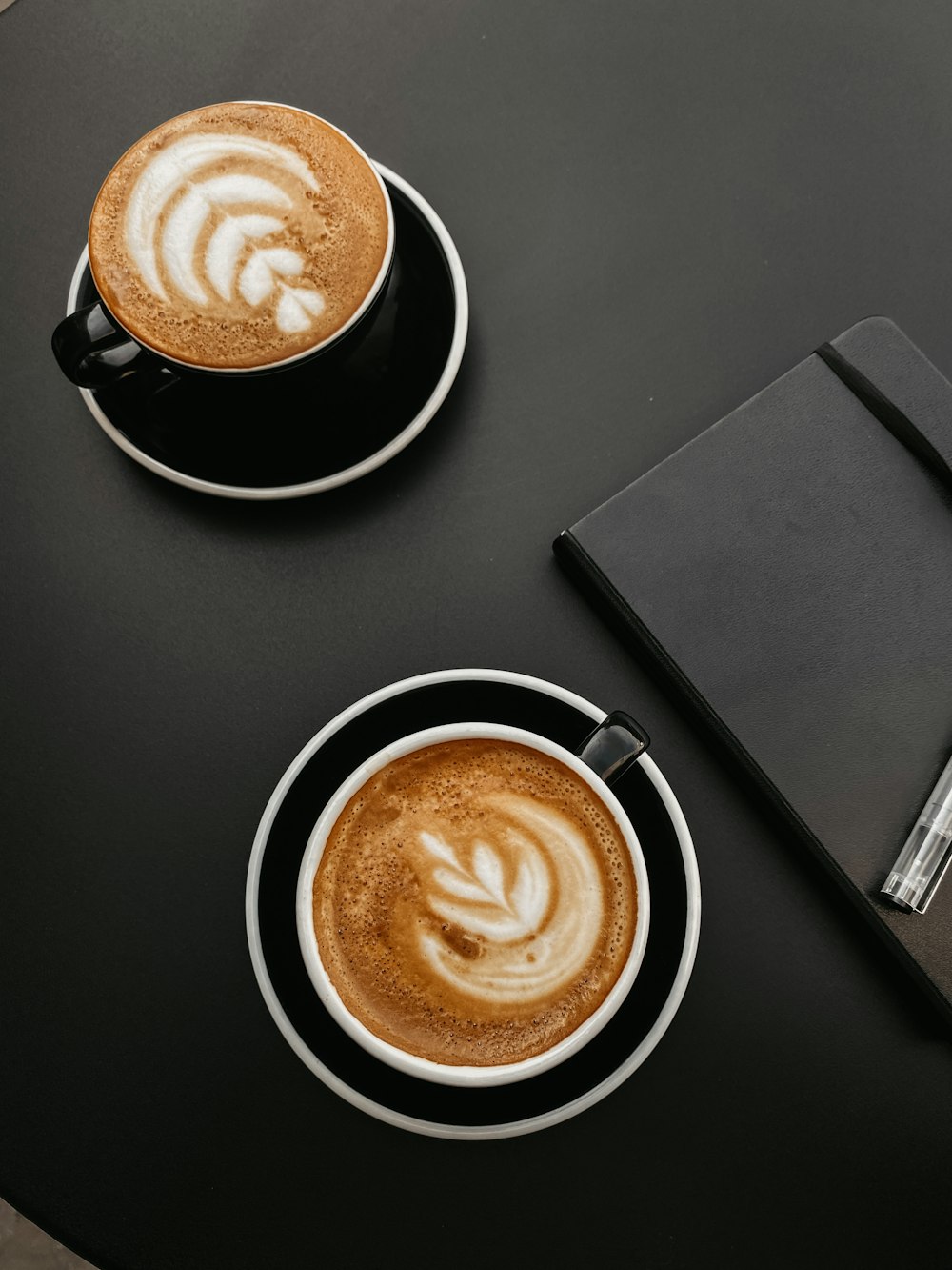 two cups of cappuccino on a black table