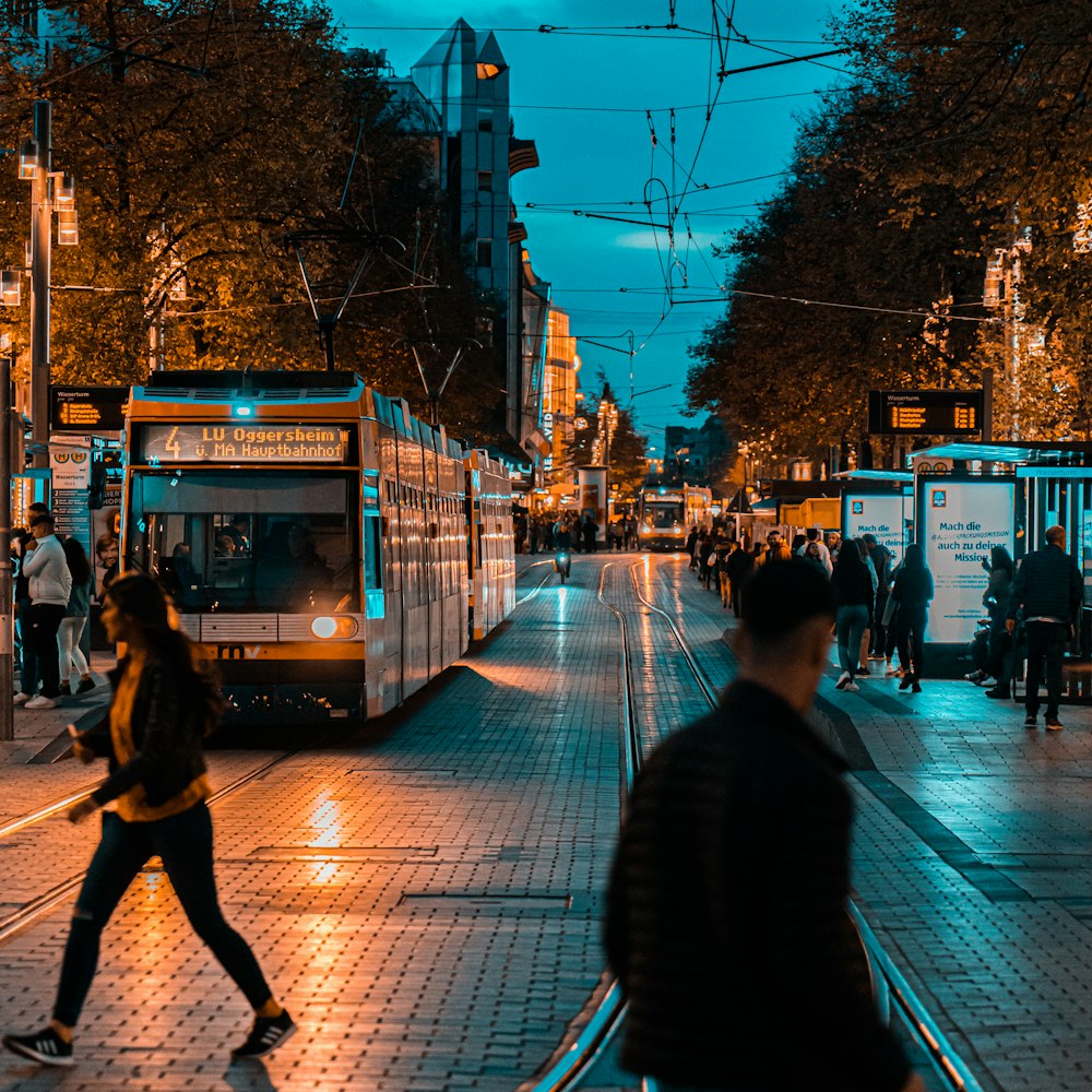 a group of people walking down a street next to a train