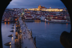 Panoramic view from Prague Castle overlooking the city rooftops and winding river below.