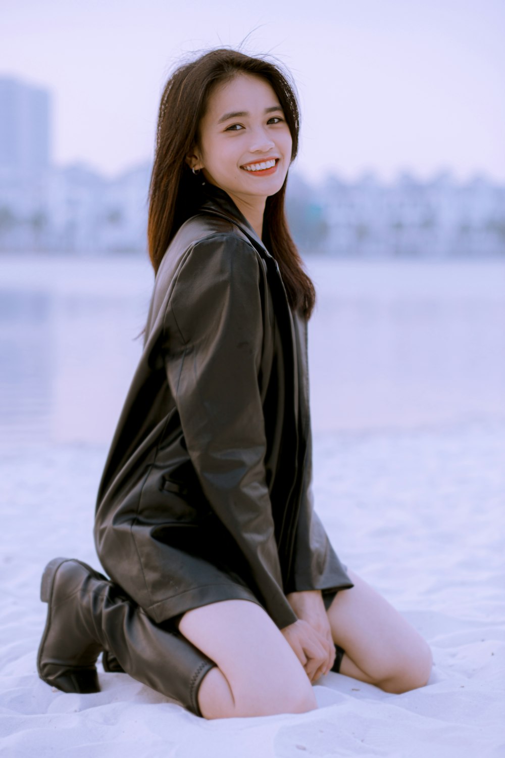 a woman is sitting on the beach posing for a picture