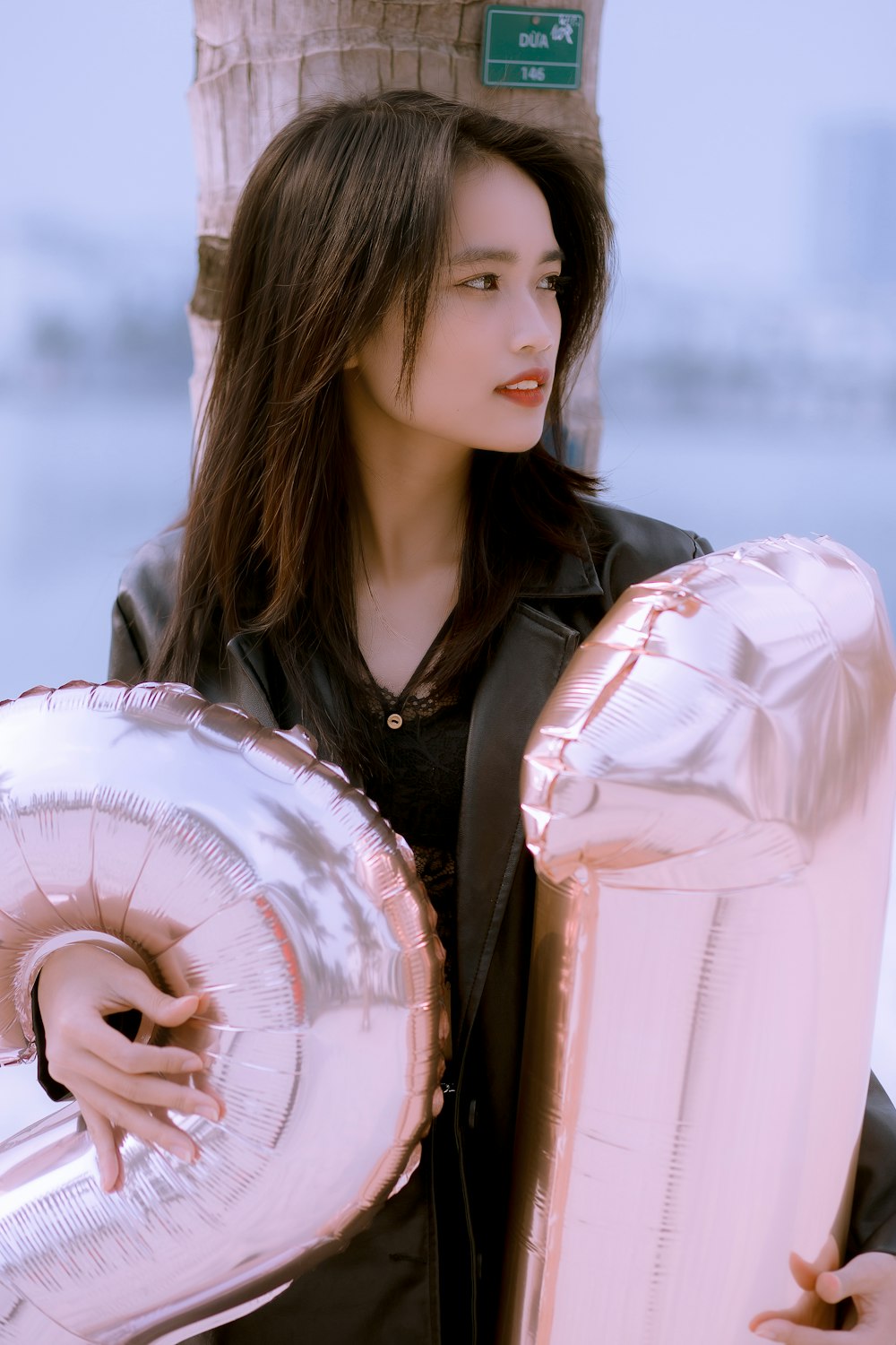 a woman holding two large silver and gold foil balloons