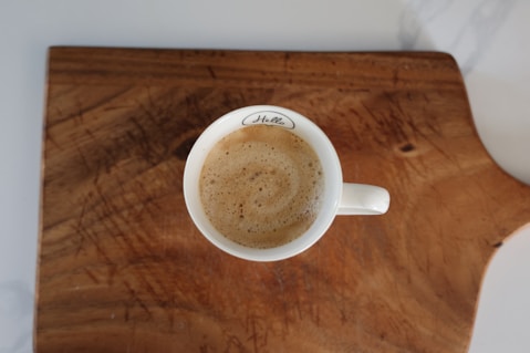a cup of coffee sitting on top of a wooden cutting board