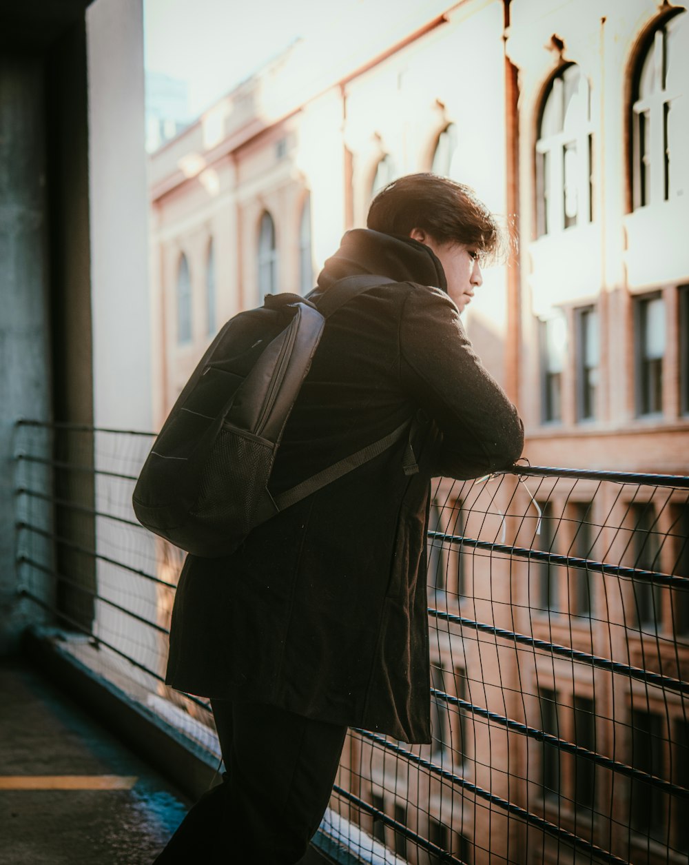 a man standing on a balcony with a backpack on his back