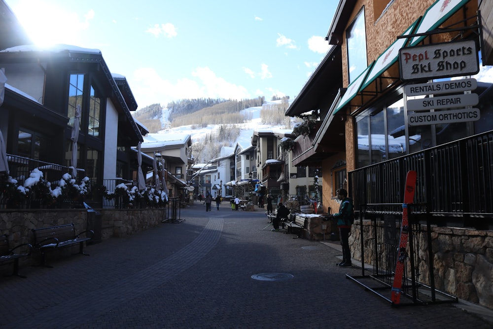 a street lined with snow covered buildings next to a mountain