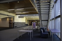 a room with a staircase and tables and chairs