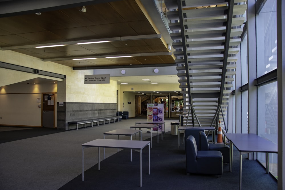 a room with a staircase and tables and chairs