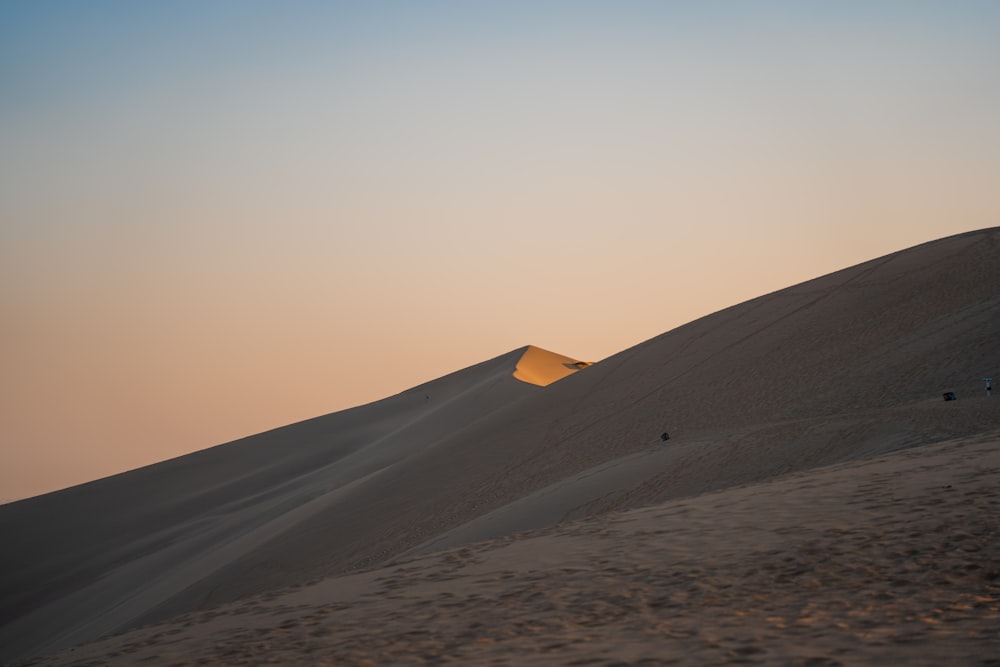 the sun is setting over a sand dune