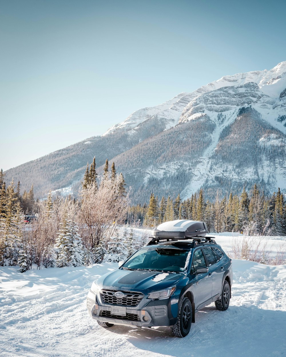 a car parked in the snow in front of a mountain